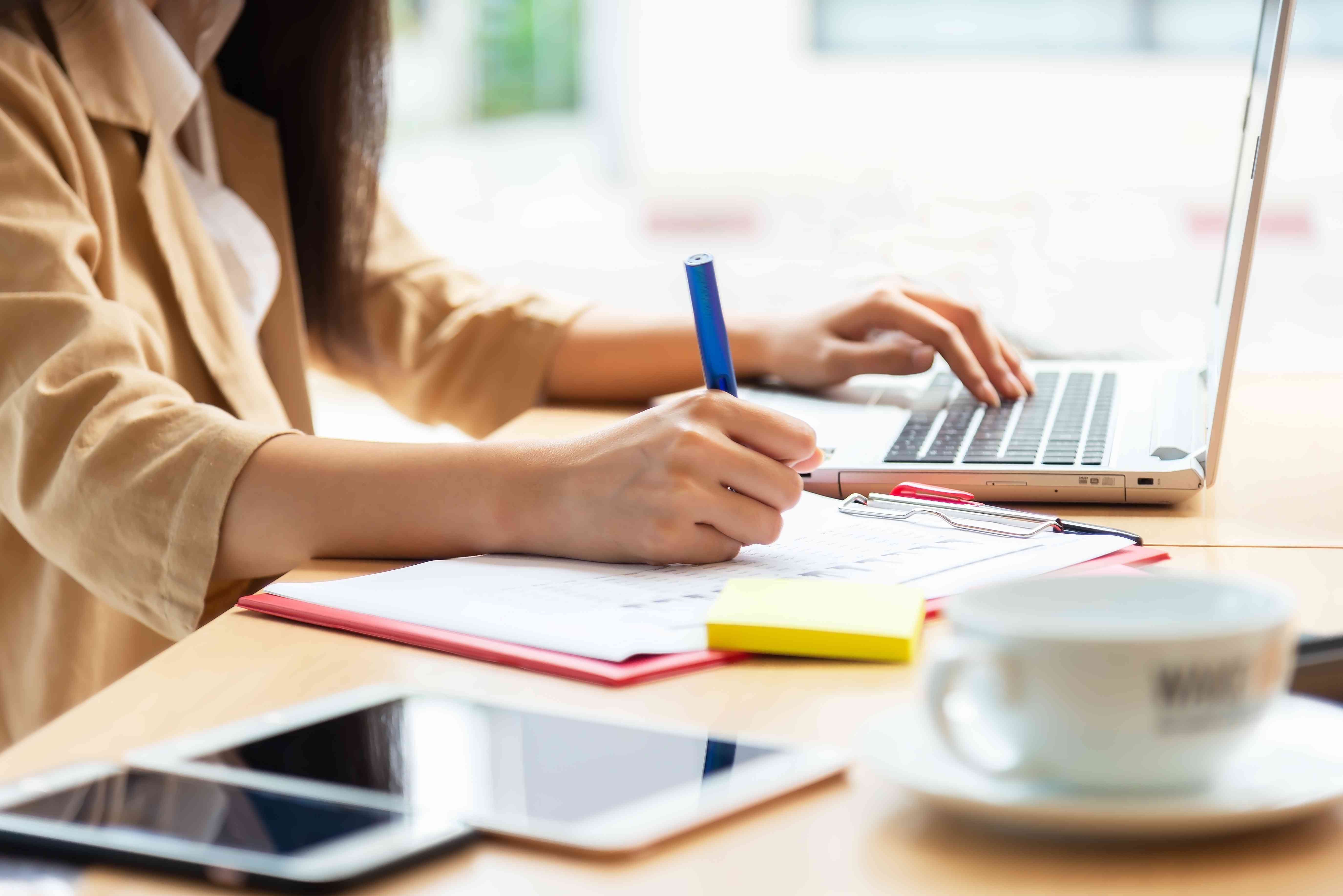 Asian woman using laptop at home while sitting the wooden table.hands typing on the notebook keyboard. Online training education and freelance work. Computer, laptop and studying remotely.