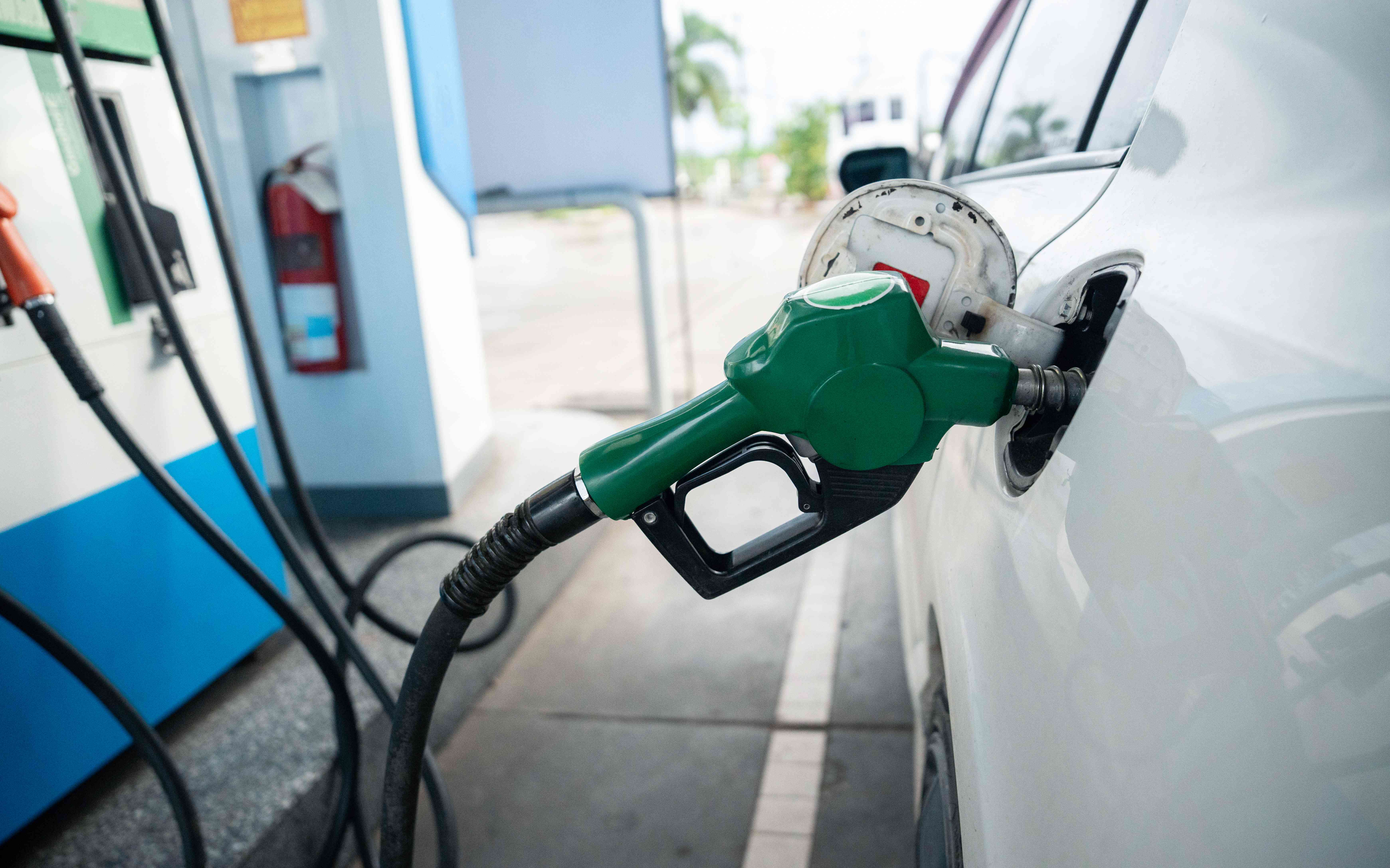 A gas pump is left refilling a car's gas tank at a gas station