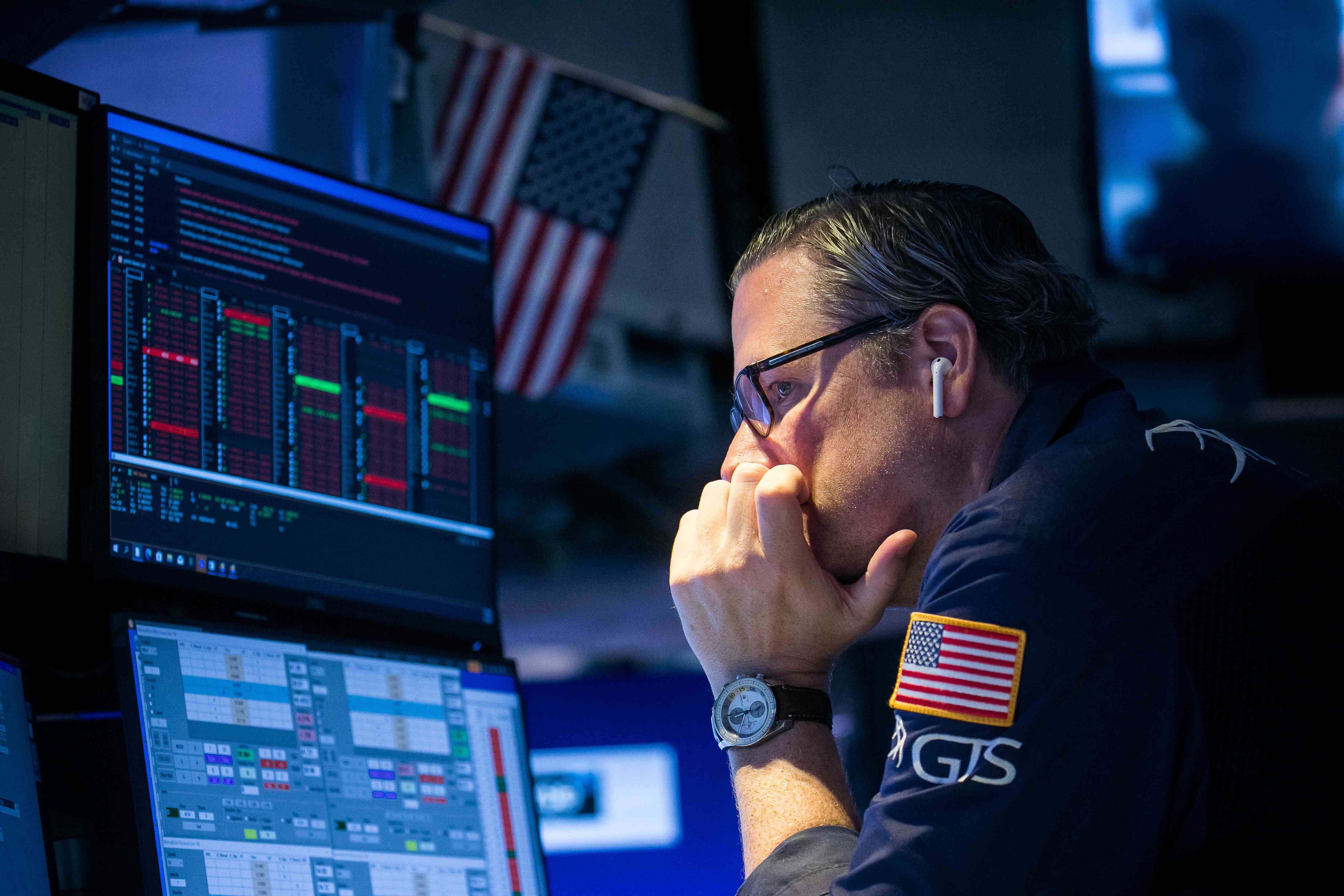 A trader looks at computer screens on the floor of the New York Stock Exchange, leaning his chin in the palm of his hand.