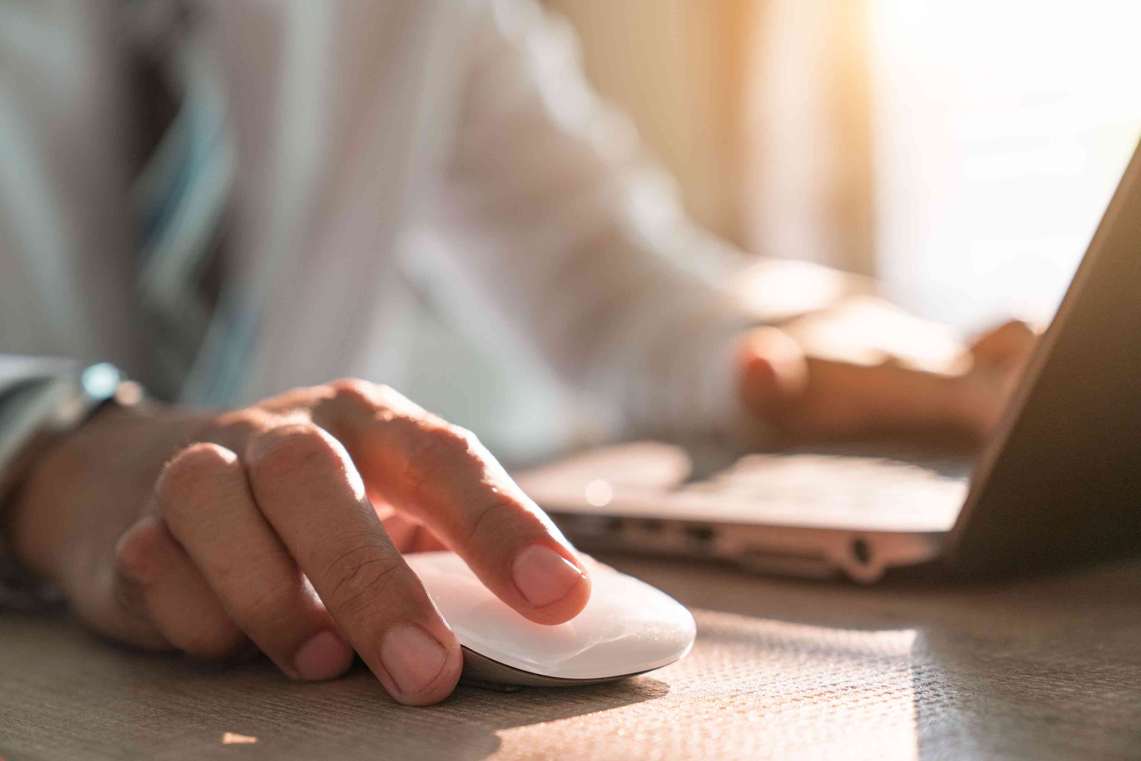 Businessman hand holding computer mouse with laptop keyboard