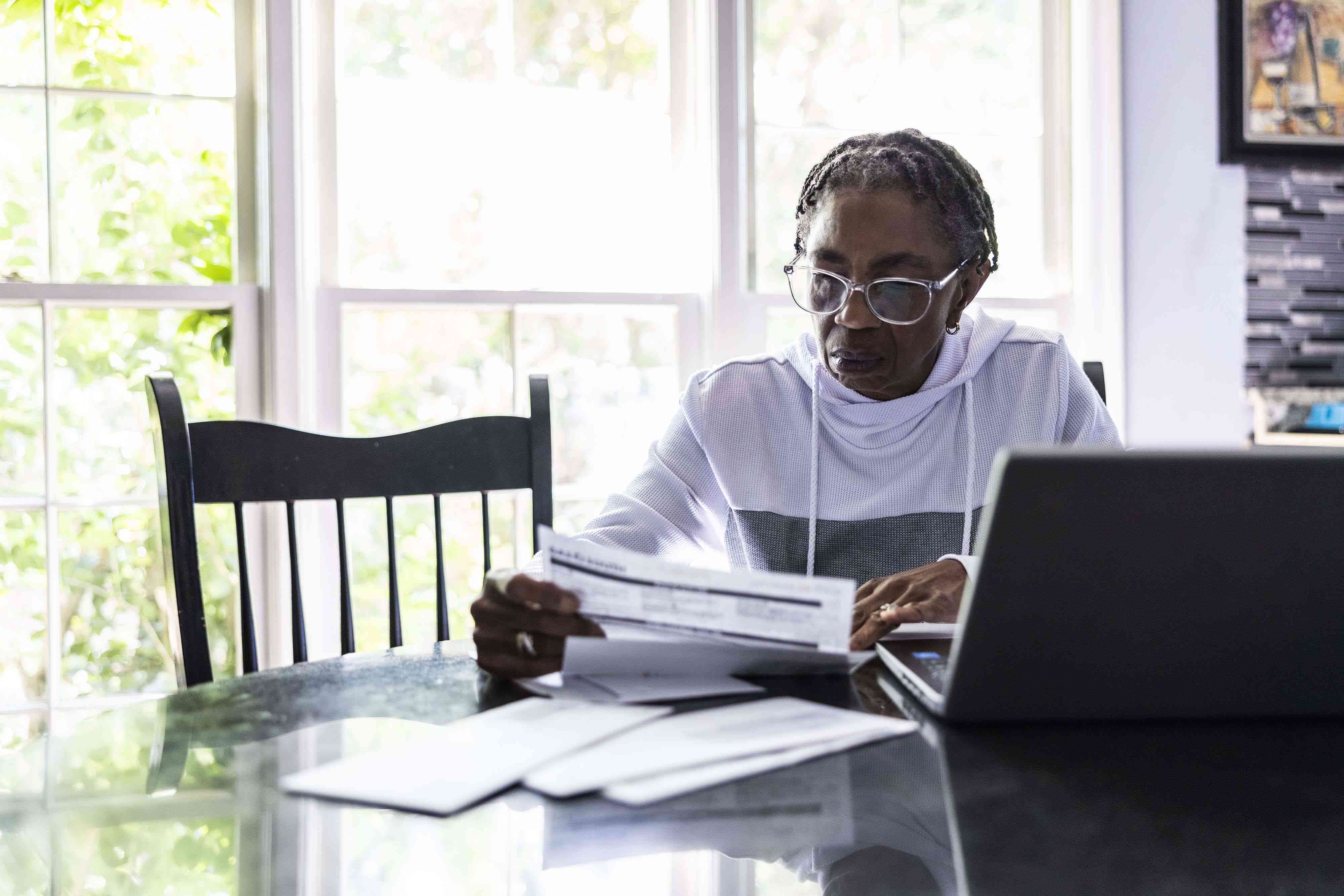 Woman paying bills using her laptop at her kitchen table